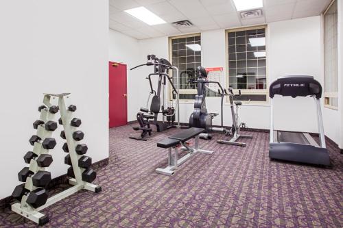 a gym with treadmills and machines in a room at Ramada by Wyndham Red Deer Hotel & Suites in Red Deer