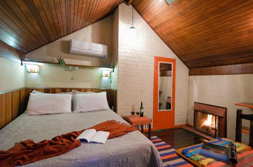 a bedroom with a bed with two books and a fireplace at Pousada Colher de Chá - chalés in Visconde De Maua