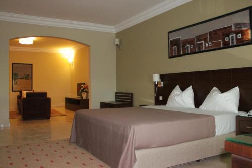 a hotel room with a large bed and a chair at Hotel Mauricenter Nouakchott in Nouakchott