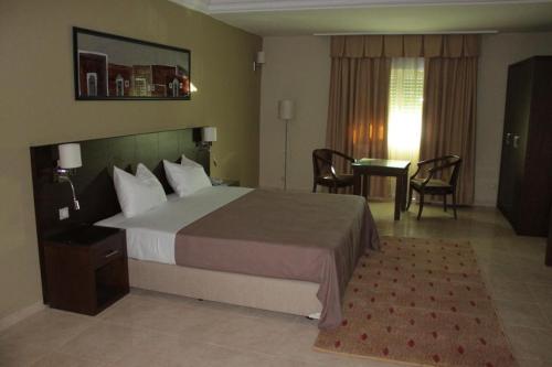 a hotel room with a bed and a table and chairs at Hotel Mauricenter Nouakchott in Nouakchott