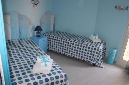 2 camas individuais num quarto com paredes azuis em Maré - Scala dei Turchi em Realmonte