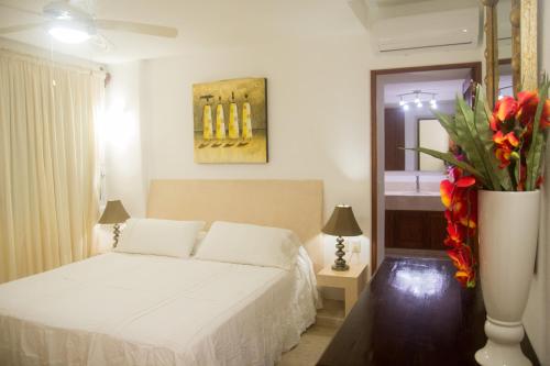a bedroom with a bed and a vase of flowers at Los Mangos in Zihuatanejo