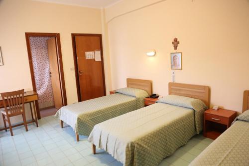 Habitación de hotel con 3 camas y mesa en Casa Piccole Ancelle di Cristo Re, en Roma