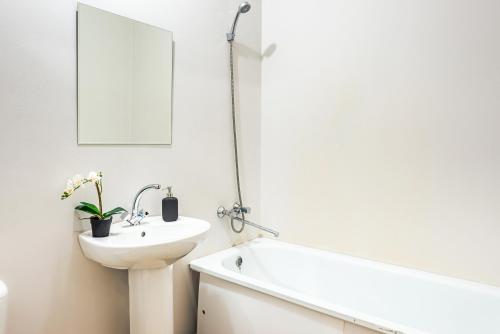 a white bathroom with a sink and a bath tub at Уютных апартаментов GOOD HOUSE Дорожная 18 in Yekaterinburg