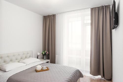 a bedroom with a bed and a large window at Уютных апартаментов GOOD HOUSE Дорожная 18 in Yekaterinburg
