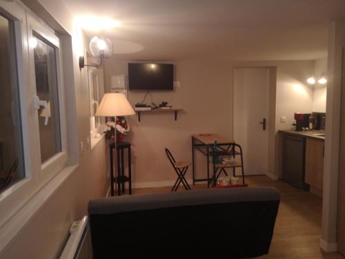 a living room with a couch and a table at Charmante Maison studio proche mer et commerces in Ouistreham
