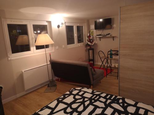 ein Wohnzimmer mit einem Bett und einer Lampe in der Unterkunft Charmante Maison studio proche mer et commerces in Ouistreham