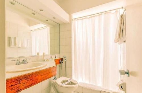 a bathroom with a toilet and a sink and a mirror at Hotel Cristina Suites in Puerto La Cruz