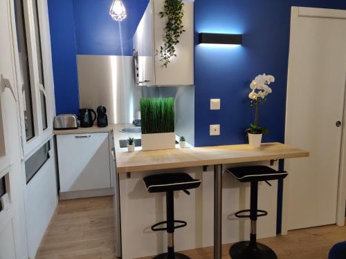 une cuisine avec un comptoir avec des tabourets et un mur bleu dans l'établissement T2 Lounge & Design - Toulouse Centre Ramblas, à Toulouse
