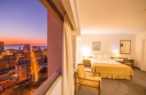 Habitación de hotel con cama y vistas a la ciudad en Hotel Cristina Suites, en Puerto La Cruz