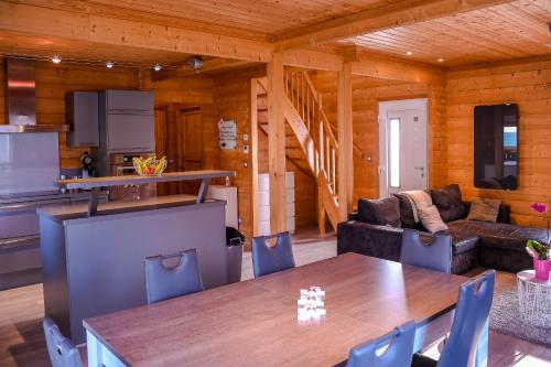 una cucina e un soggiorno con tavolo in una cabina di Insolite maison bois, wifi Netflix, au coeur de l'Argonne et des batailles de Verdun a Chaudefontaine