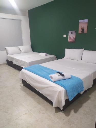 Hotel Maria del Mar في Planeta Rica: سريرين في غرفة بجدران خضراء