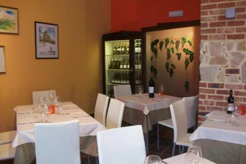 a restaurant with tables and white chairs and wine bottles at B&B l'Angolo di Rosina con ristorante in Novello