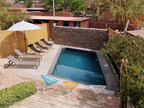 a swimming pool with chairs and an umbrella at Hotel Jardin Atacama in San Pedro de Atacama