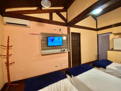 a bedroom with two beds and a flat screen tv at Pousada Kyrios in Maresias