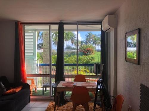 ein Wohnzimmer mit einem Tisch und einem großen Fenster in der Unterkunft Bonheur à la résidence Savane in Le Gosier