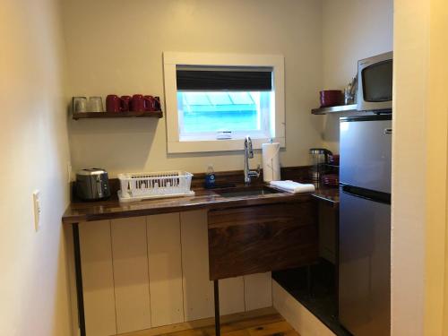 una pequeña cocina con fregadero y nevera. en Trailside Inn, en Killington
