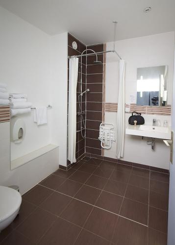 a bathroom with a shower and a toilet and a sink at The Originals City, Hôtel Continental, Poitiers in Poitiers