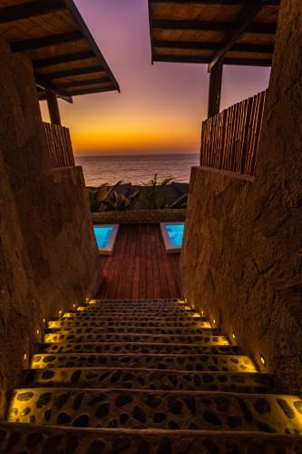 a stairway leading to a beach with a sunset in the background at Casas Lua & Mar - Vichayito - Máncora in Vichayito