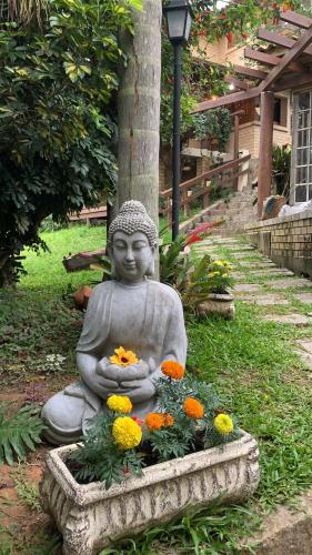 a statue sitting in the grass with flowers at Hostel Vale do Rosa in Praia do Rosa