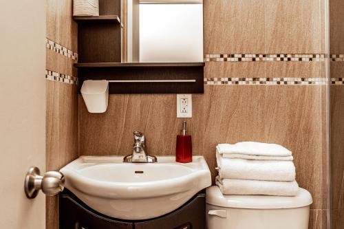 een badkamer met een wastafel, een toilet en een spiegel bij Cjour Apartments in Montreal