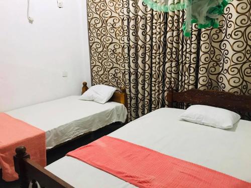 a room with two beds and a curtain at Tharuka Rest Inn Hotel in Tanamalwila