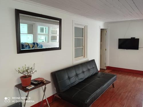 un sofá de cuero negro en una sala de estar con espejo en Hospedaje curicó casa grande, en Curicó