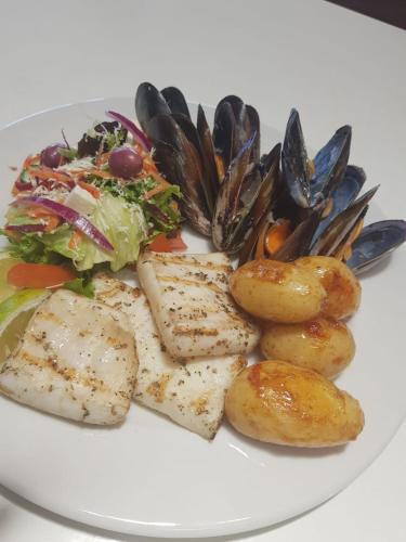 a plate of food with fish and potatoes and a salad at Friday Island in Langebaan