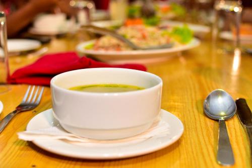 a cup of soup sitting on a plate on a table at Hotel Blue Sky in Kurunegala
