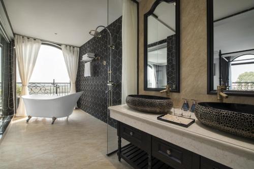 a bathroom with two sinks and a tub and mirror at Lalita Boutique Hotel & Spa Ninh Binh in Ninh Binh