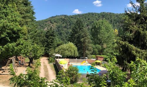 a swimming pool with umbrellas next to a forest at Camping Les Berges Du Doux in Colombier-le-Vieux