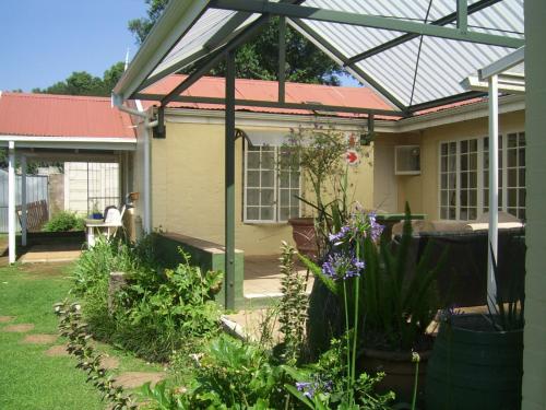 a pergola over a house with a garden at Nutmeg Guest House in Howick