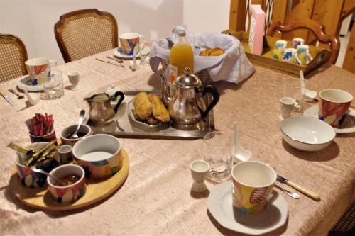 una mesa con tazas y platos y un hervidor de agua. en Le vieux pont, en Saint-Julien