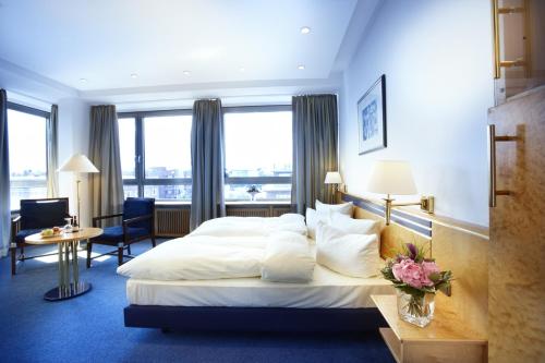 ein Hotelzimmer mit einem großen Bett und einem Schreibtisch in der Unterkunft Hotel Astor Kiel by Campanile in Kiel