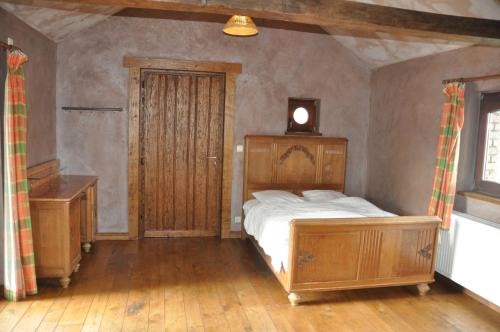 a bedroom with a wooden bed and a wooden door at Gîte Ferme d'Ortie in Sainte-Ode