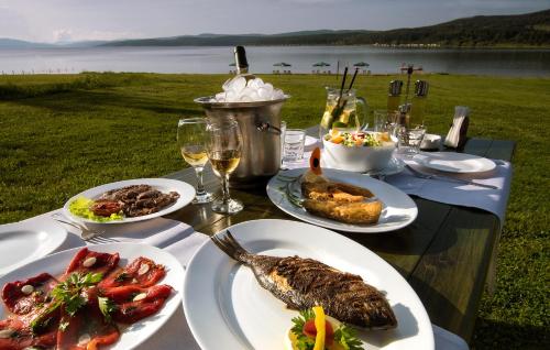 a table with plates of food and wine glasses at Комплекс Будното око The Beach in Pasarel