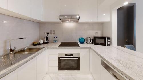 a white kitchen with a sink and a microwave at SUHA Mina Rashid Hotel Apartments in Dubai