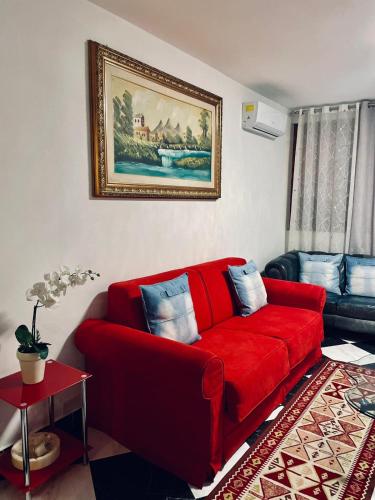 a red couch in a living room with a painting at CASA DEI FIORI in Somma Lombardo