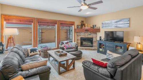 a living room with leather furniture and a fireplace at I Spy - Cozy Pet Friendly, Ski In Ski Out Condo with Private Hot Tub in Big White