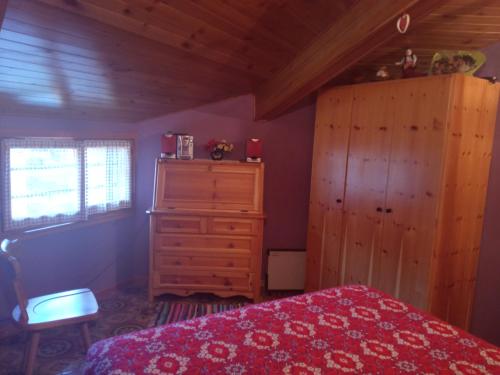 1 dormitorio con cama roja y armario de madera en Tra sogni e realtà Roccaraso, en Roccaraso