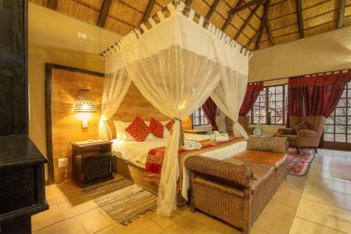 a bedroom with a canopy bed and a chair in a room at Lovely holiday home bordering Kruger National Park in Marloth Park