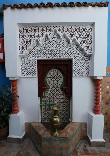 a fireplace in a room with a tile wall at Riad Hiba in Meknès