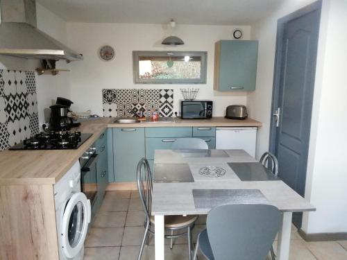 a kitchen with blue cabinets and a table and chairs at Au fil de l'eau in Conchy-sur-Canche