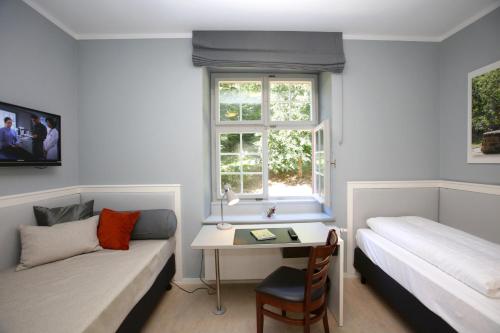 a bedroom with a bed and a desk and a window at Jugendstilhotel Trifels in Annweiler am Trifels