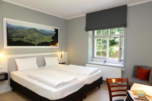 Un dormitorio con una gran cama blanca y una ventana en Jugendstilhotel Trifels, en Annweiler am Trifels