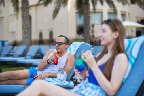 a man and a woman sitting on a bench eating food at Bahi Ajman Palace Hotel in Ajman 