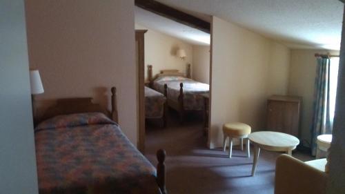 a hotel room with two beds and a table at La Fleur de Lys in Cormatin