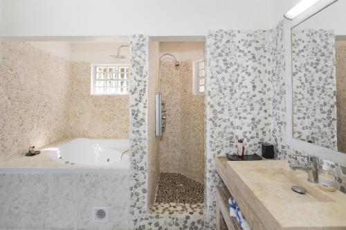 een badkamer met een bad, een wastafel en een douche bij Orient Bay Villa Rentals St Martin in Orient Bay
