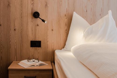 a bed with a lamp and a book on a night stand at Niciora in Badia