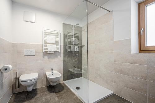 a bathroom with a toilet and a glass shower at Niciora in Badia